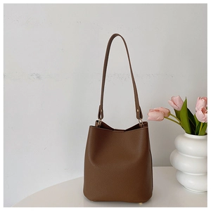 Detail of brown litchi pattern leather bucket bag with slim shoulder strap for women