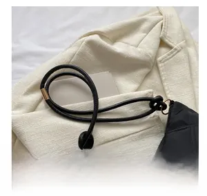 Detail of black quilted handbag with unique thick rope knot handle and metallic rings