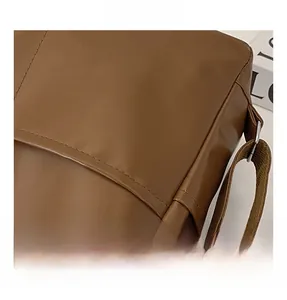 Close-up of brown leather tote bag showing smooth texture and metal strap hardware