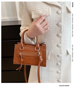 Detail of caramel brown pebbled leather handbag featuring front tassel zipper and arc handle