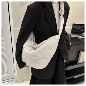 Detail of white quilted half-moon shoulder bag with a stylish knotted strap design