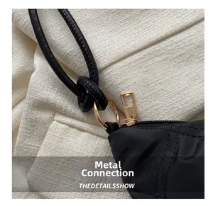 Macro detail of black nylon bag showing gold metal rings and knotted rope shoulder strap
