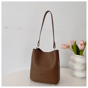 Detail of lychee pattern leather texture and gold hardware on dark brown bucket bag