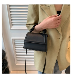 Détail du petit sac carré en cuir noir avec poignée nouée et bandoulière amovible