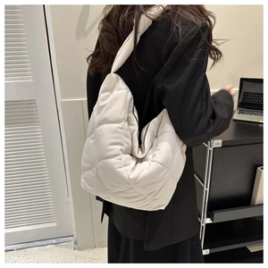 Detail of white quilted puffer shoulder bag with large diamond stitching and wide strap