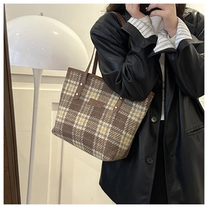 Detail der Vintage-Tweed-Tasche mit Karomuster, Lederriemen und Markenaufnäher