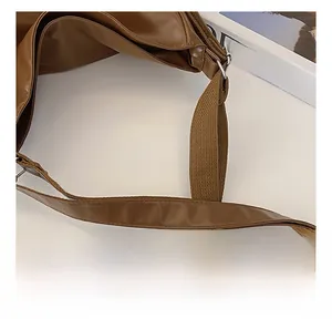 Detail of the brown leather shoulder strap and silver metal buckle on a retro tote bag