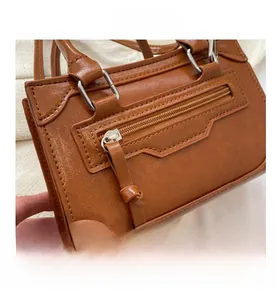 Close-up of caramel leather handbag with silver hardware and vintage luggage style stitching