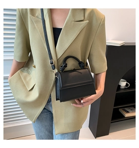 Détail d'un sac à main noir avec poignée nouée porté avec un blazer vert élégant
