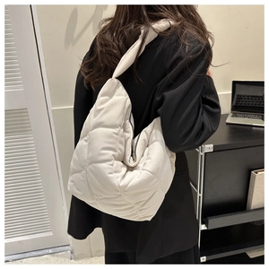 Detail of cream quilted puffer bag showing heart stitching and soft nylon texture