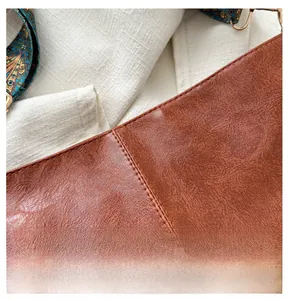 Detailed macro view of the brown leather texture and stitching on this bucket tote bag
