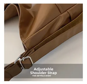 Close-up of adjustable brown leather shoulder strap with silver metal buckle and stitching