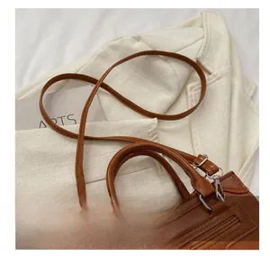 Detail of brown vintage crossbody bag showing comfortable strap and top handle design
