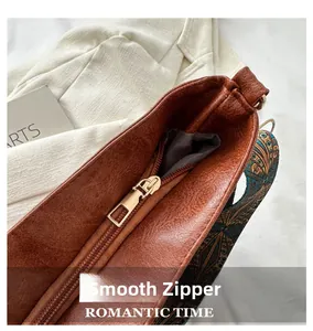 Close-up of smooth gold zipper and colorful woven strap on brown lychee grain tote bag