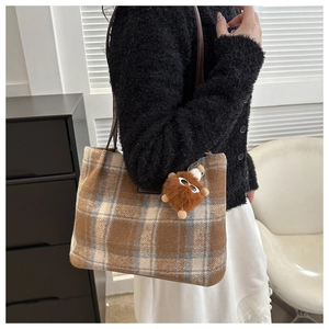 Detailed view of checkered wool tote bag with plush charm and dark brown leather straps