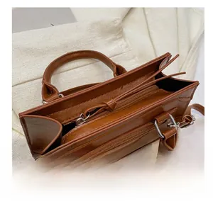 Close-up of smooth metal zipper detail on a vintage brown leather square handbag