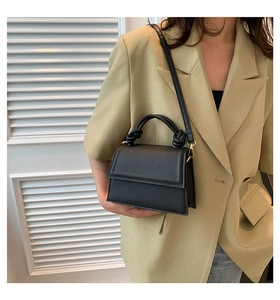 Détail d'un sac à main en cuir noir avec poignée nouée et finitions métalliques dorées