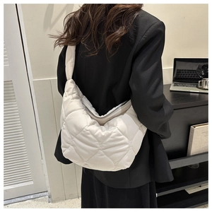 Rear view of a model wearing a white quilted crescent bag with a plush puffer texture