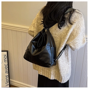 Detail of black pebbled leather tote bag styled with a cream oversized knit sweater