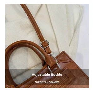 Detail of adjustable silver buckle on brown lychee grain leather handbag strap