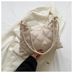 Detail of beige quilted shoulder bag with silk-gloss finish and gold ring hardware
