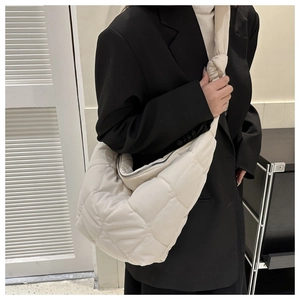 Detail of quilted puffer crossbody bag with soft padding and knots on shoulder strap