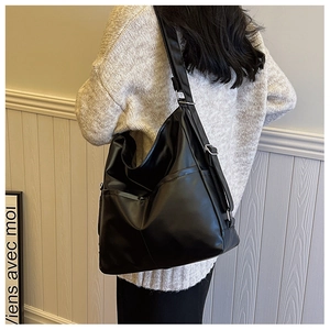 Detail view of large black crossbody bag with adjustable strap on a model shoulder