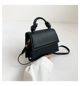 Détail du sac à main en cuir PU noir avec poignée nouée et crochets métalliques dorés