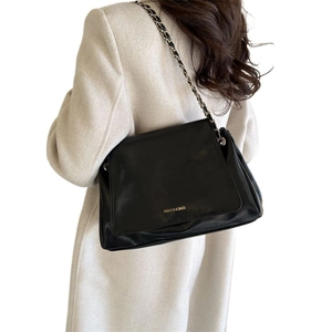Large black leather tote bag with woven chain strap shown on model in urban style
