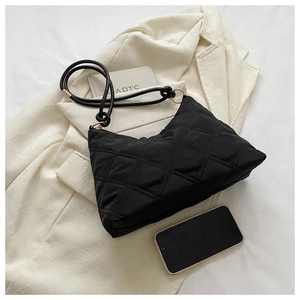 Detail of black quilted shoulder bag with fine straps and gold hardware on blazer background