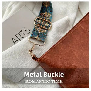 Detailed close-up of golden metal hardware clasp and woven strap on brown leather bag