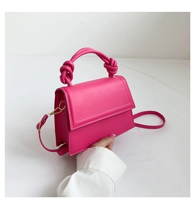 Détail d'un mini sac bandoulière fuchsia avec poignée nouée unique et texture en cuir PU