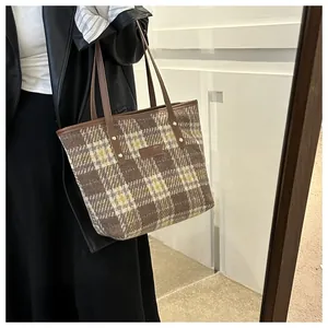 Details der braunen Tweed-Tragetasche mit Lederriemen und goldenen Nietenverzierung