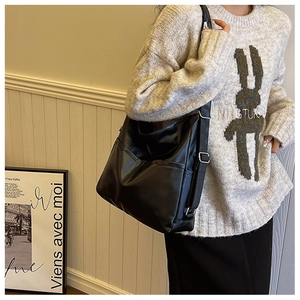 Detail view of large black matte tote bag with dual front pockets and wide shoulder strap