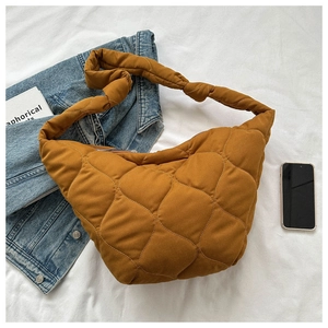Close-up of brown quilted tote bag with soft padding and wide shoulder strap detail