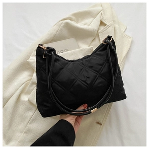Close-up of quilted black nylon bag featuring gold metal rings and zipper detail