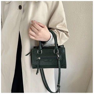 Detail of vintage dark green leather crossbody bag showing metal buckle and zipper texture