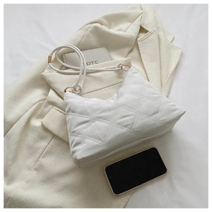 Detailed shot of white quilted puffy handbag with knot shoulder strap on beige jacket