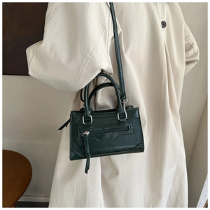 British style forest green textured leather crossbody bag styled with a beige trench coat