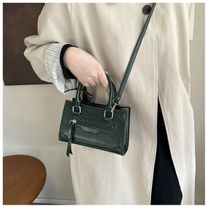 Model carrying a vintage dark green mini tote with silver hardware and long tassels