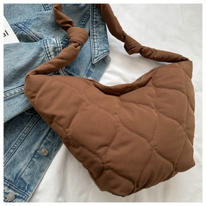 Detail of a brown quilted nylon shoulder bag with a knotted strap and diamond patterns
