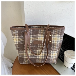 Detailansicht der karierten Woll-Tasche mit Lederriemen auf einem hölzernen Schreibtisch