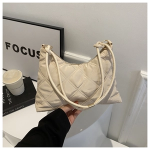 Close-up of quilted cream beige hobo bag with metal rings on a minimalist display