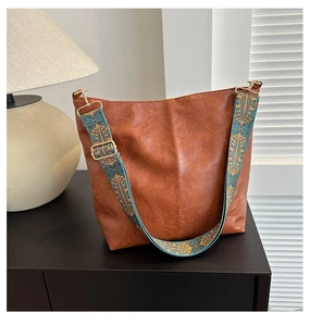 Detail of vintage brown PU leather tote bag with elegant blue and gold embroidered strap