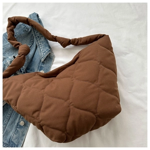 Detail of brown quilted tote bag with knot strap design and puffy diamond texture