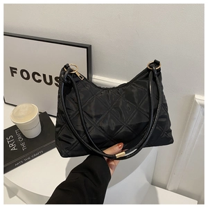 Macro view of black quilted nylon dumpling bag with refined diamond pattern and leather handle
