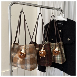 Detailed display of three wool plaid tote bags in brown, coffee and green with plush charms