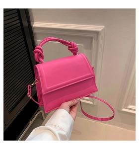 Détail de la poignée nouée rose rouge et de la boucle dorée sur le sac à bandoulière