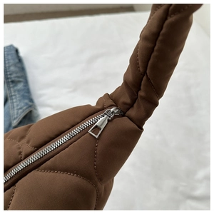 Detailed close-up of the silver metal zipper and quilted texture on a brown padded bag