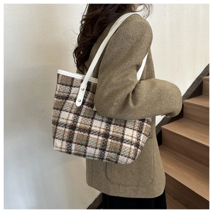 Nahaufnahme der Vintage-Karotasche aus Tweed mit weißen Lederriemen und Goldnieten